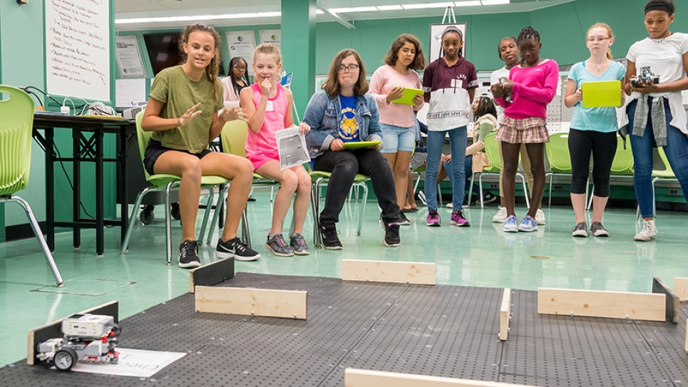 Girls program small battery-powered cars to travel through a maze using a tablet computer